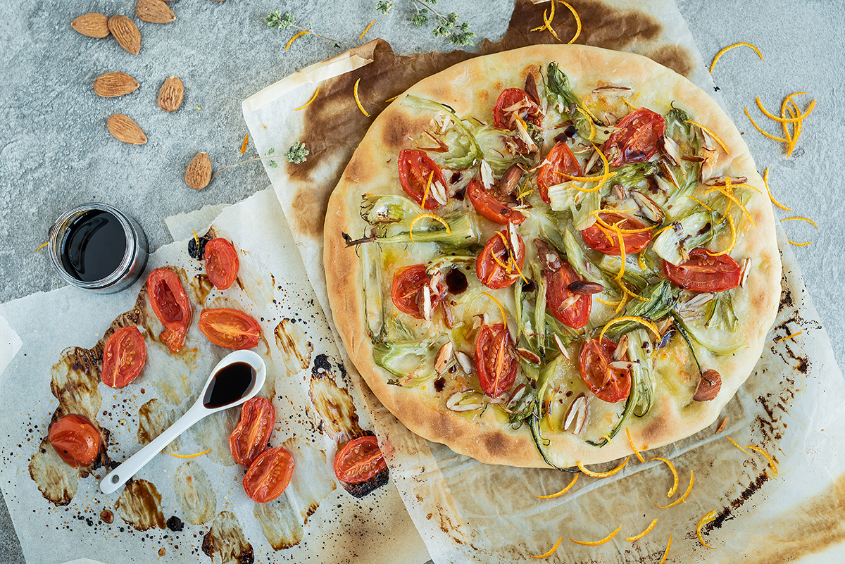 Pizza con confit di pomodori, puntarelle, mandorle e arancia
